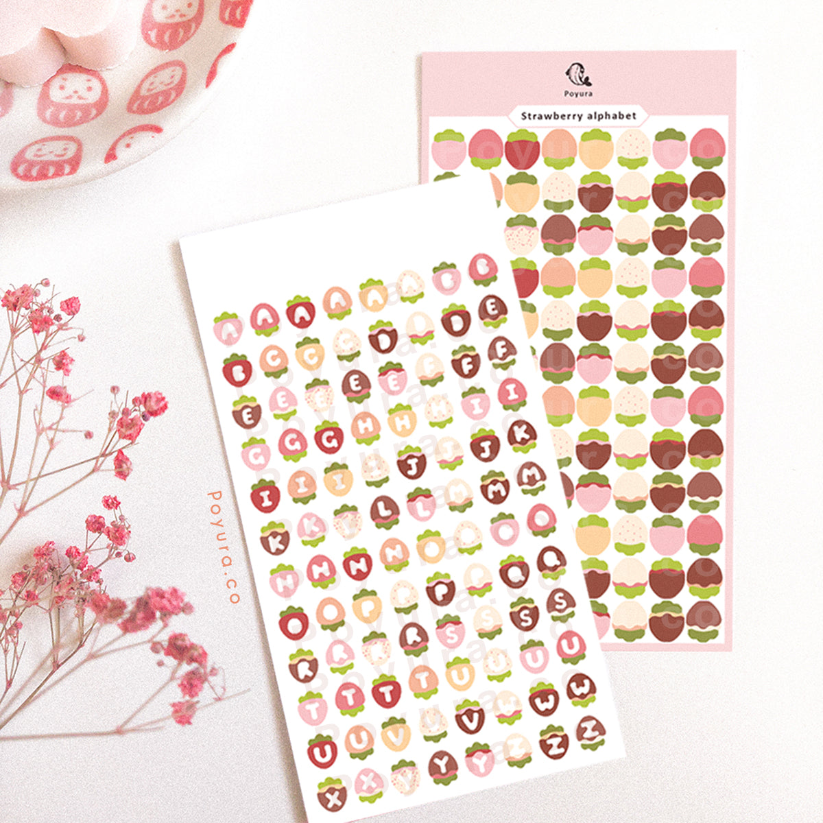 Sticker sheets of strawberries with alphabet letter cutouts in the center.