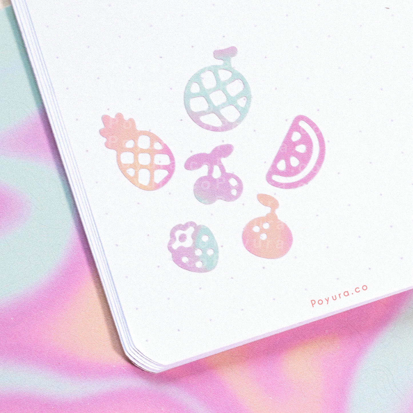 Borderless stickers with fruit cutouts in different purple, blue, and orange tints on a journal