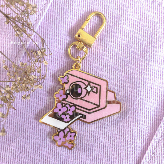 An enamel keychain of a cute retro camera with purple hydrangea