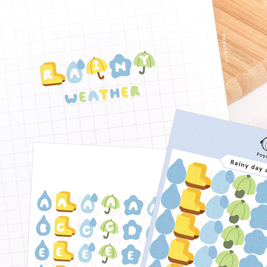 Stickers of cute rain boots and umbrellas with alphabet letter cutouts on a journal