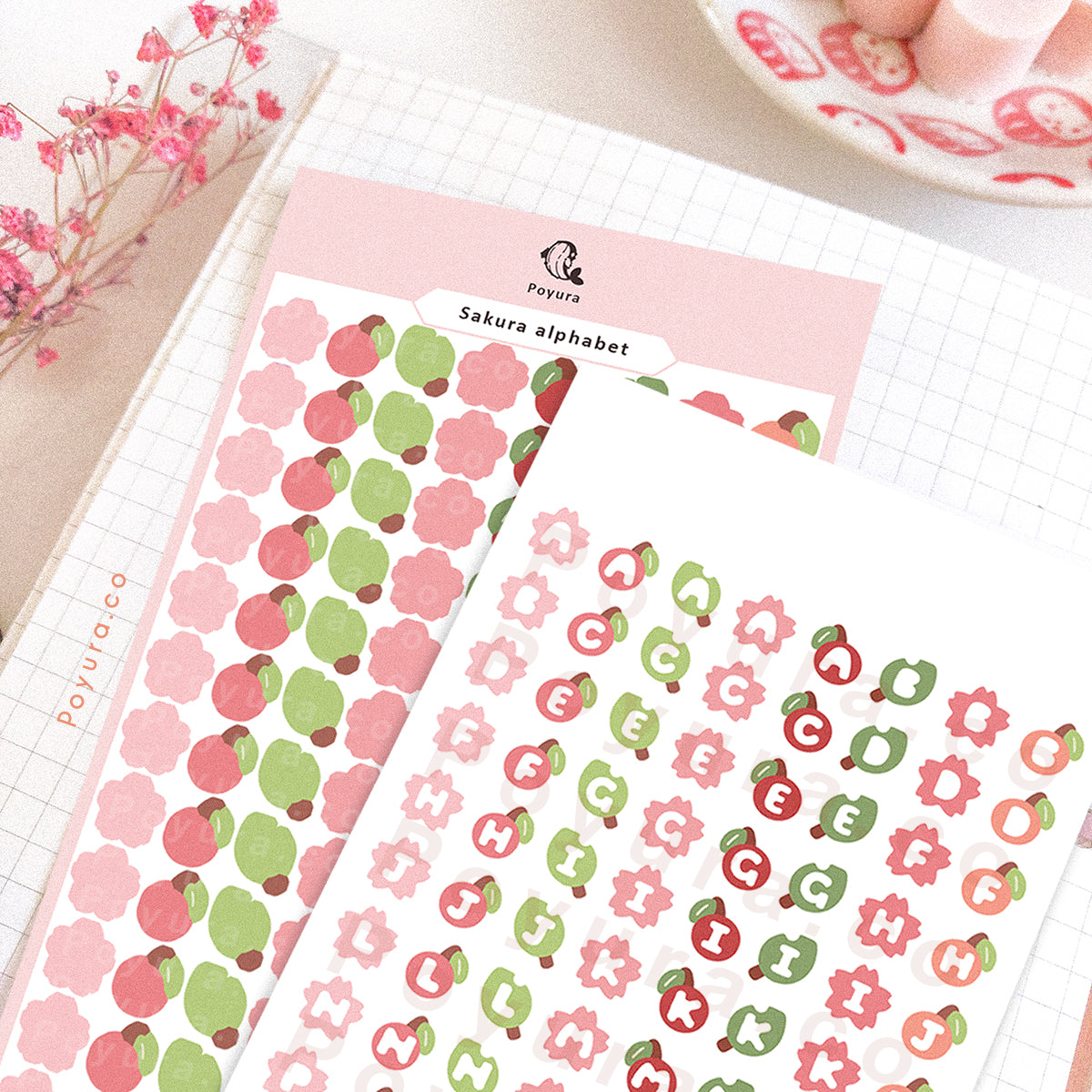 Sticker sheet of sakura, cherry, and leaves. They have alphabet letter cutouts in the center.