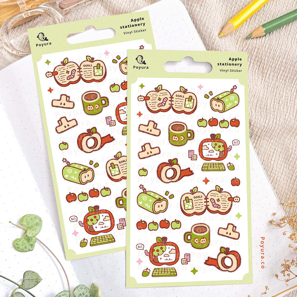 Apple stationery-themed sticker sheet on an open notebook. The desk is decorated with pencils, a scissor, and some plants.