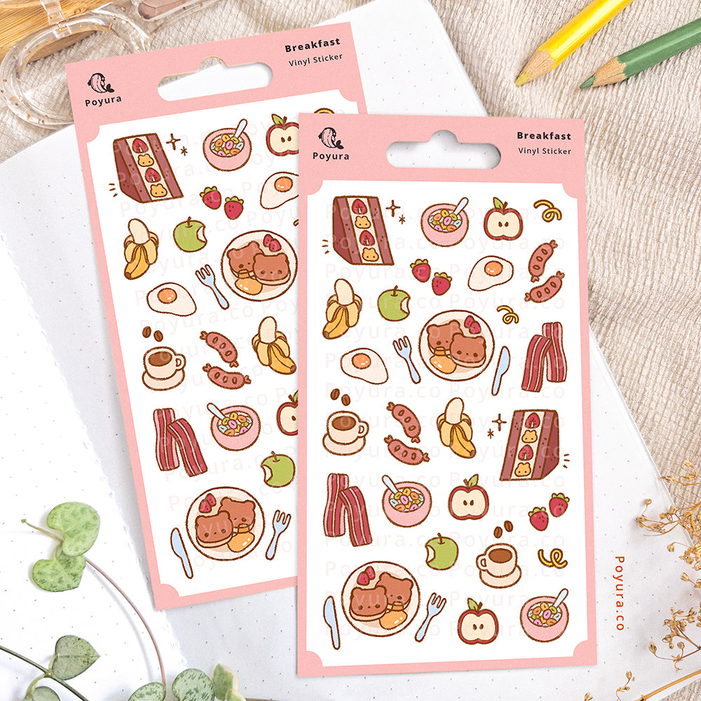 Breakfast sticker sheet on an open notebook. The desk is decorated with pencils, a scissor, and some plants.