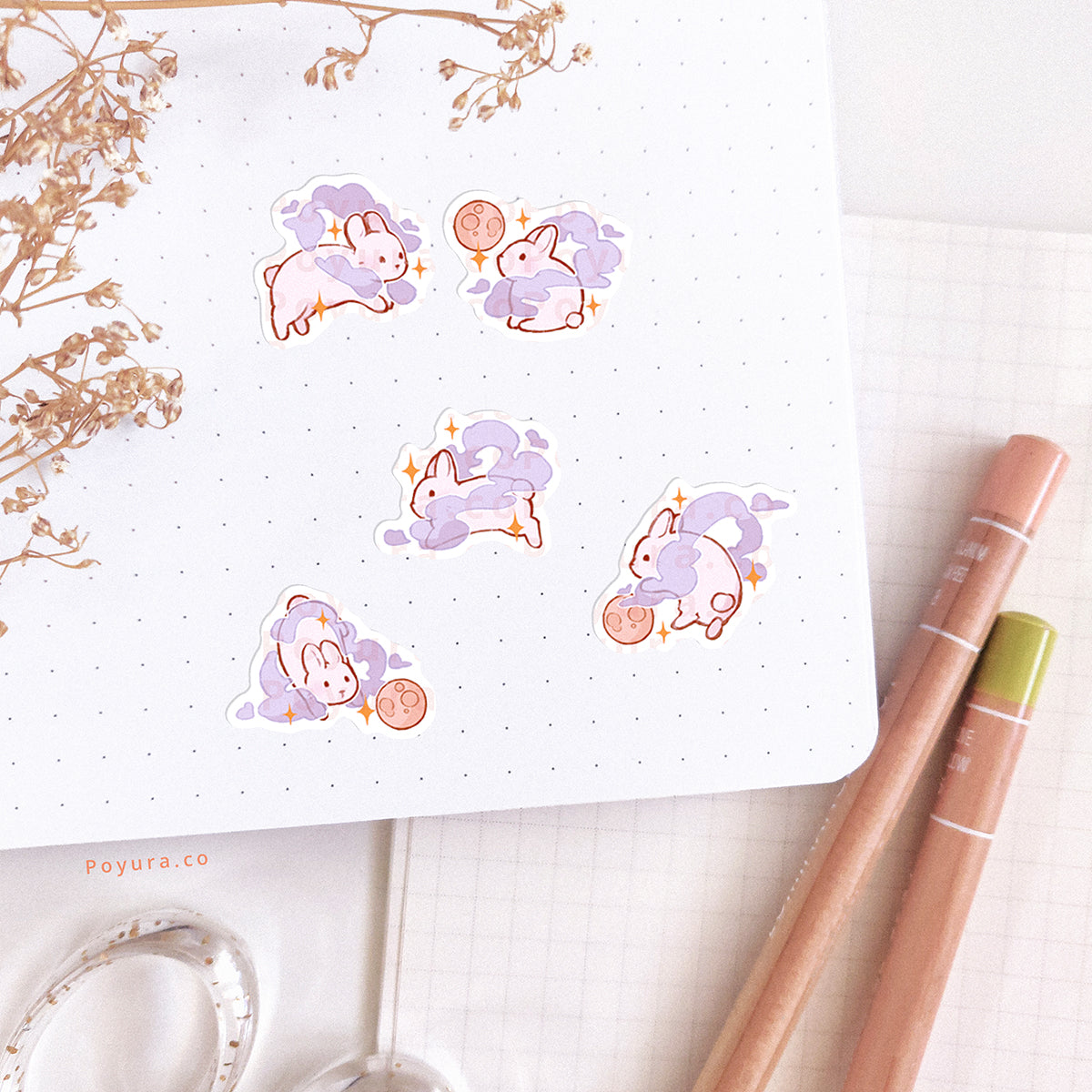 Stickers of white bunnies with a purple cloud and a moon are pasted in a journal spread.