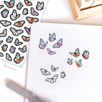 Journal spread decorated with stickers of butterflies and moths. There are blue-purple, turquoise-orange, and white butterflies.