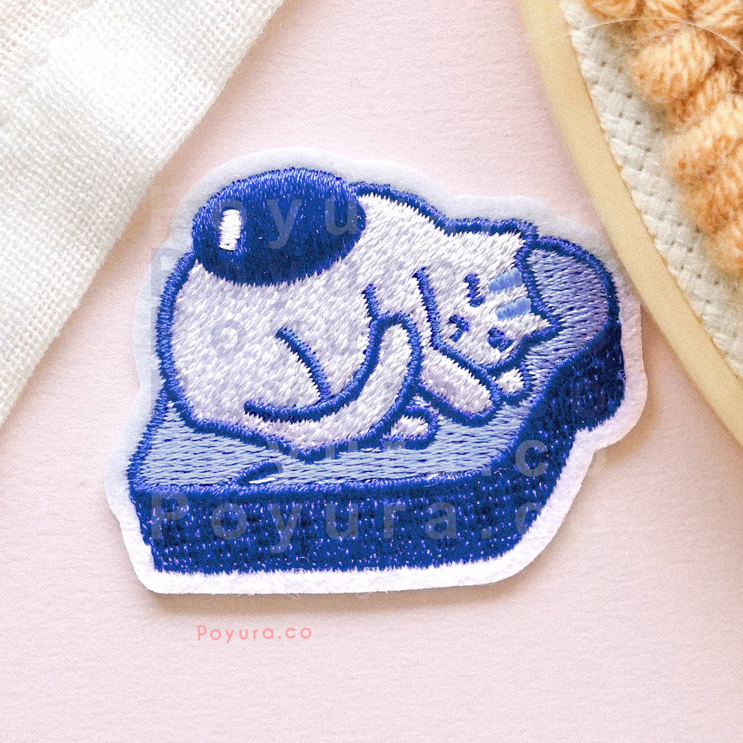 Embroidery patch of cat with an egg yolk laying on a fluffy bread