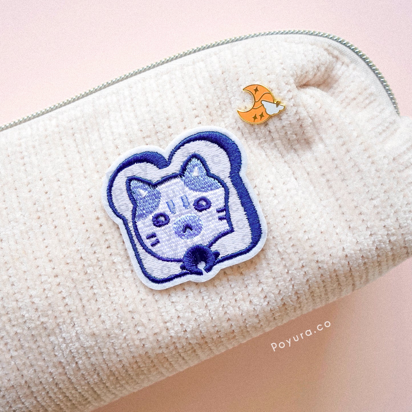 A cute blue embroidery patch of a bread with a cat head poking out