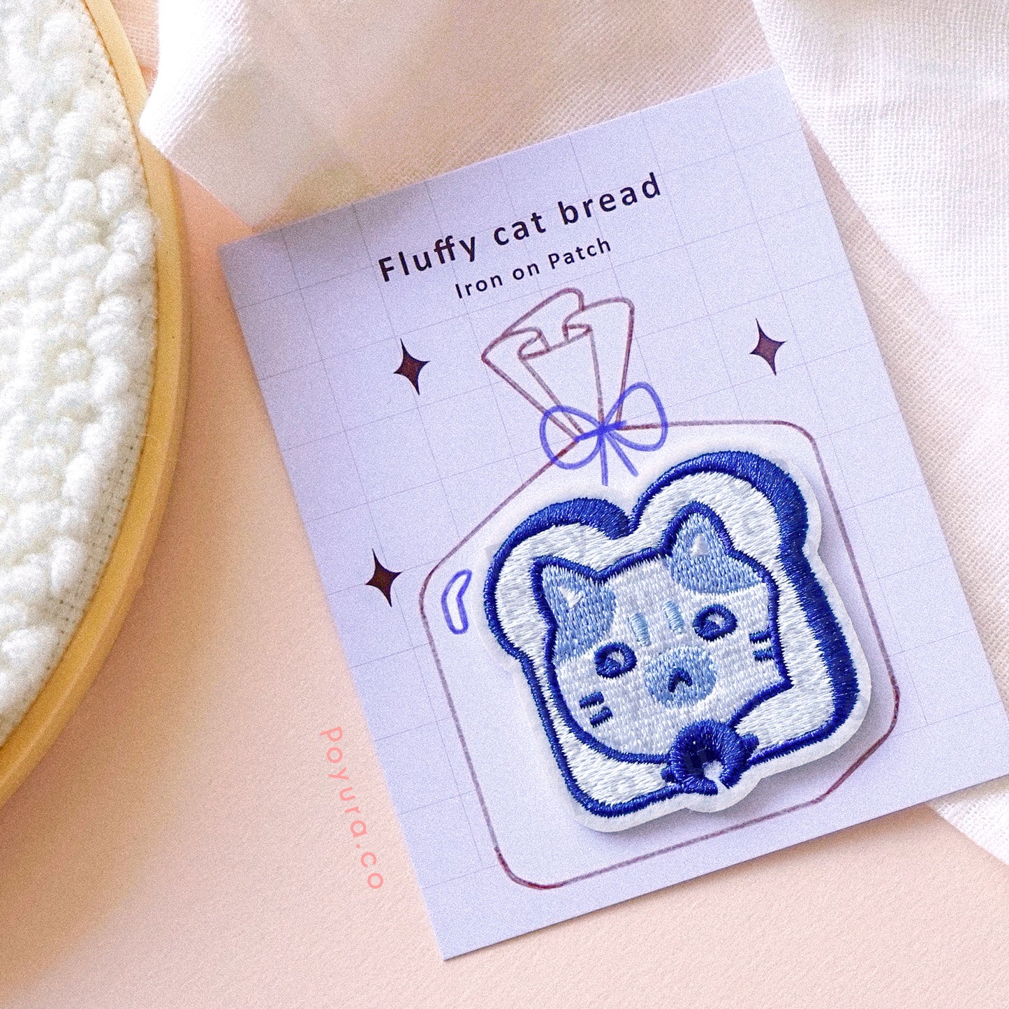 A cute blue embroidery patch of bread with a cat head poking out with packaging