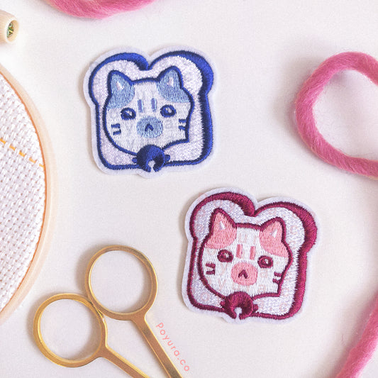 Set of one red and one blue embroidery patch of bread with a cat head poking out