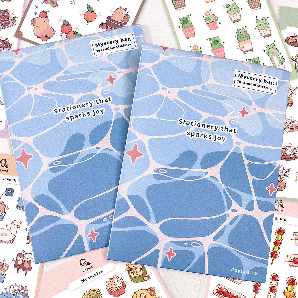 Two blue envelopes with wavy patterns and the text 'Stationery that sparks joy' and 'Mystery bag 10 random stickers' are arranged on top of a flat lay of colorful sticker sheets.
