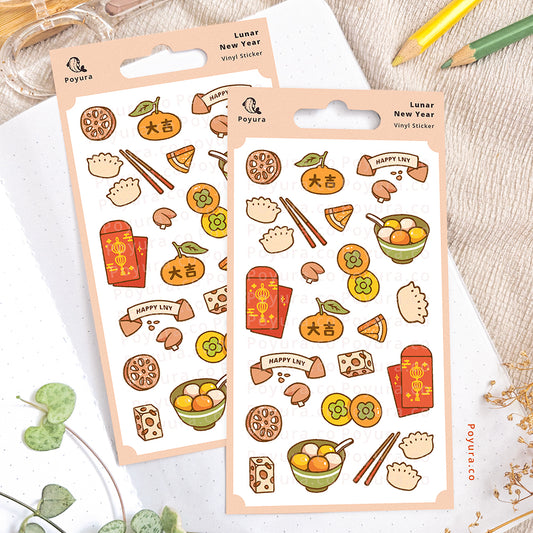 Lunar New Year sticker sheet on an open notebook. The desk is decorated with pencils, a scissor, and some plants.