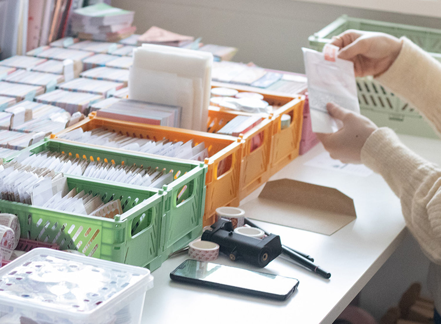 Jenny is packing orders with baskets full of stickers on the table