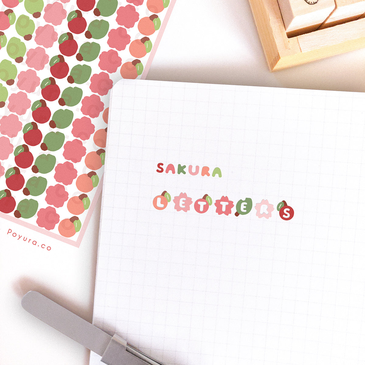 Journal spread with stickers of sakura, cherries, and leaves. The stickers have a letter cutout in the center.