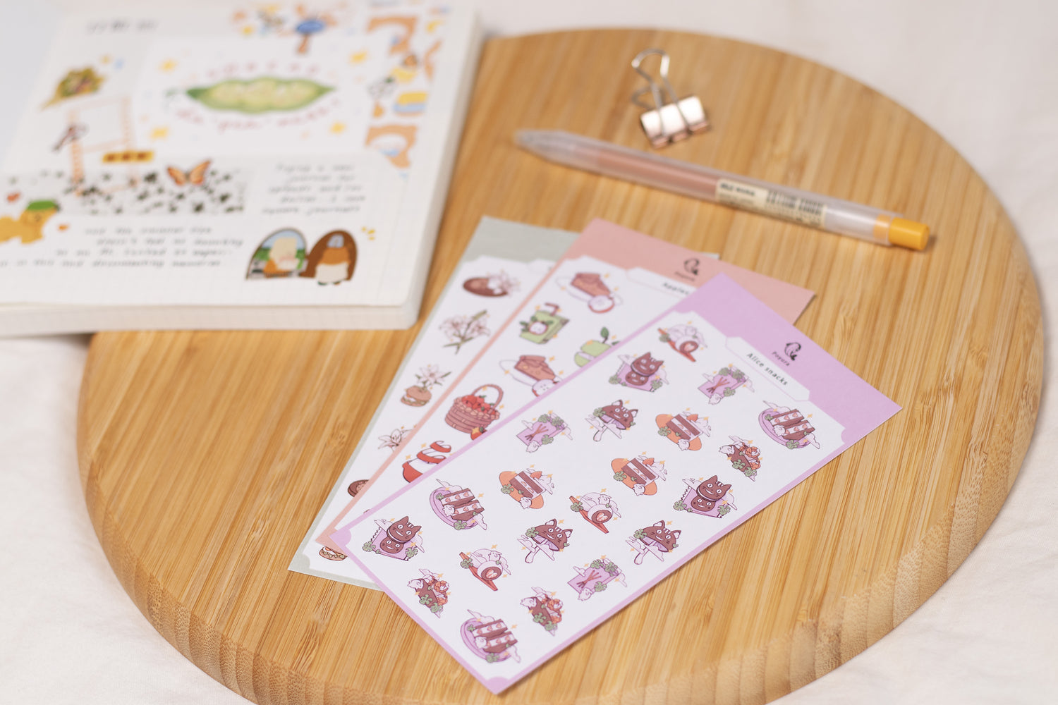 Cute stickers on a wooden board with a pen and journal around it