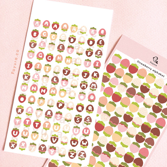 Sticker sheet of strawberries with alphabet letter cutouts in the center. 