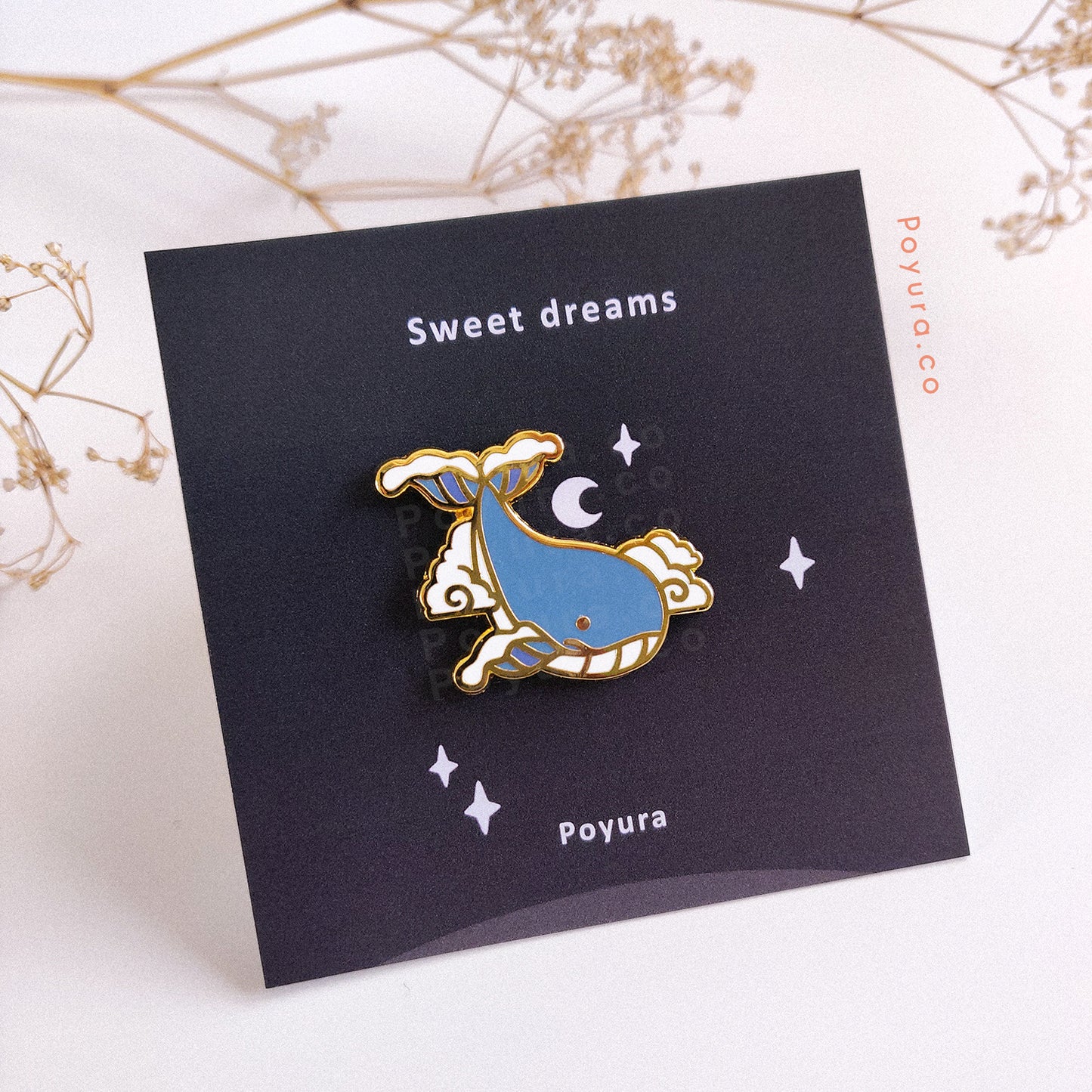 Gold enamel pin of a whale flying in the clouds