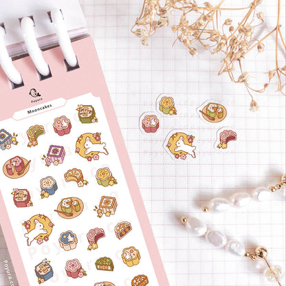 Sheet of decorative stickers with colorful bunny mooncakes on a gridded notebook with a white pen.